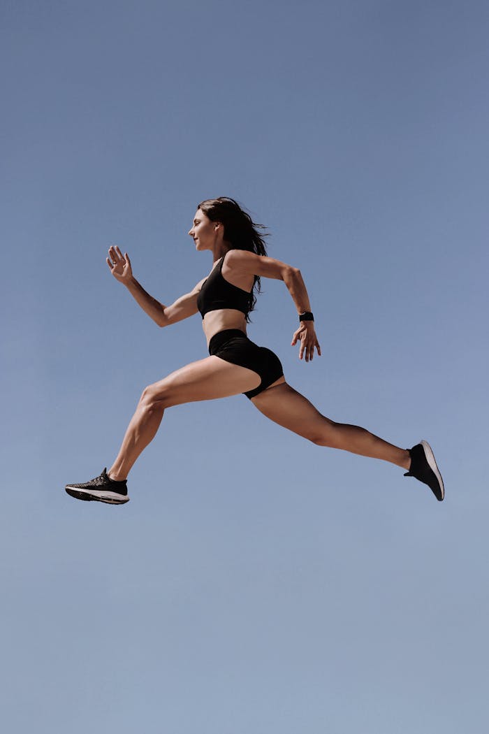 why-choose-us-01 Energetic woman in athletic wear leaping against clear blue sky, symbolizing freedom and fitness.